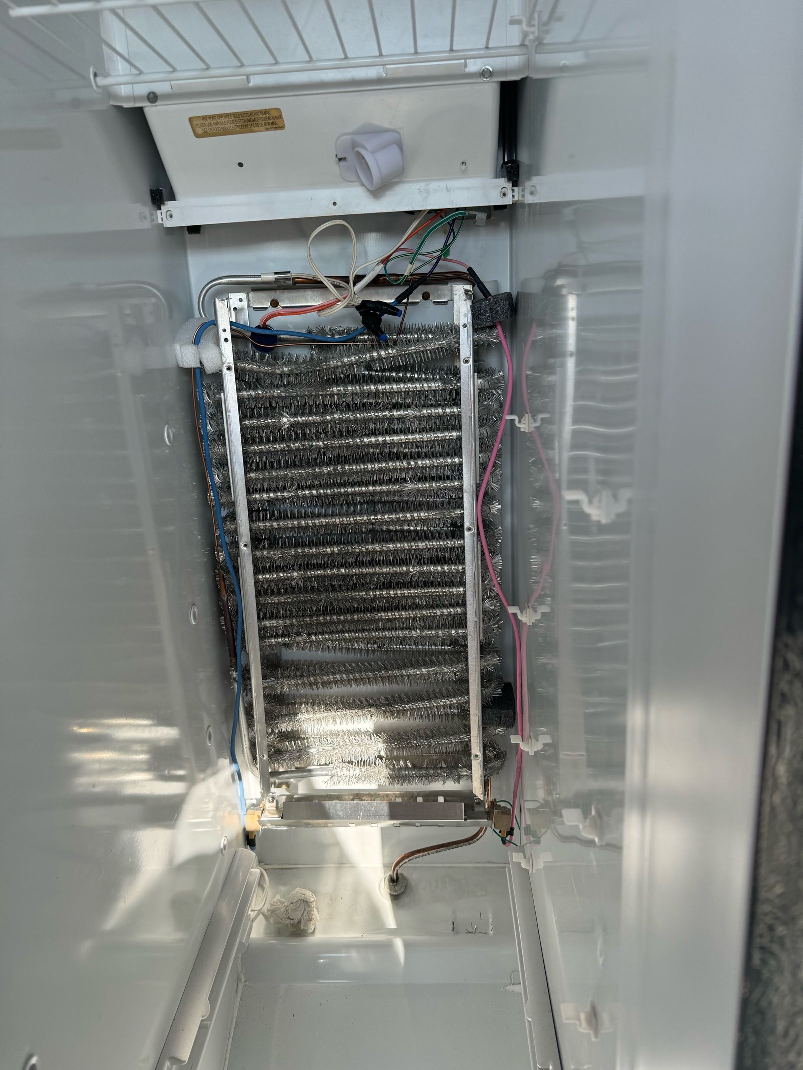 The inside of a refrigerator with a broken ice maker.
