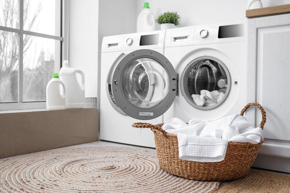 A laundry room with a washer and dryer and a basket of clothes.