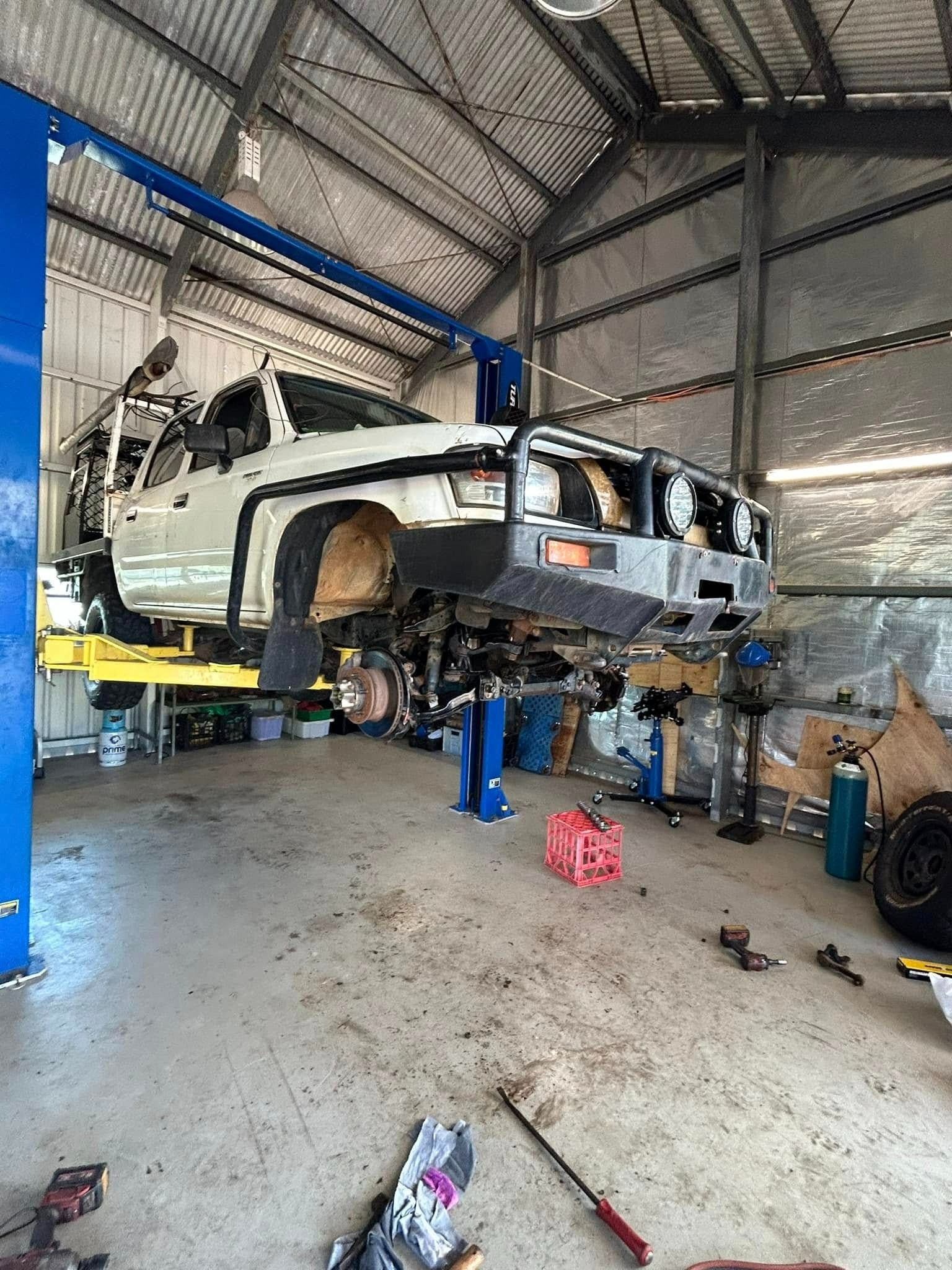 An off-road vehicle is raised on a lift inside a workshop. Disassembly is underway — Full Noise Mechanical in Humpty Doo, NT