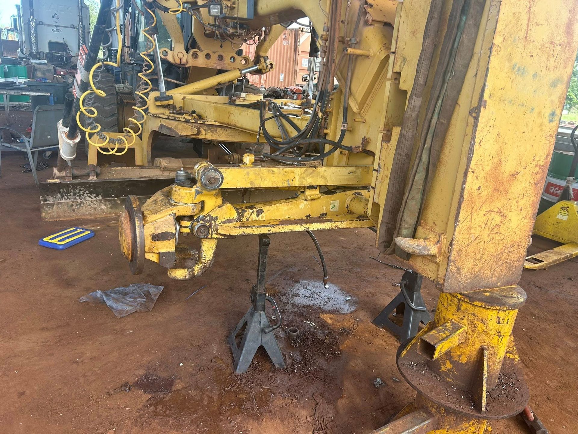 Yellow construction vehicle on jack stands, axle removed, in a workshop — Full Noise Mechanical in Humpty Doo, NT