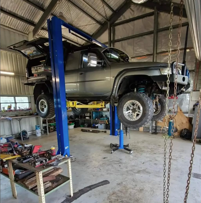 A lifted grey truck on a car lift in a workshop with tools and equipment — Full Noise Mechanical in Humpty Doo, NT