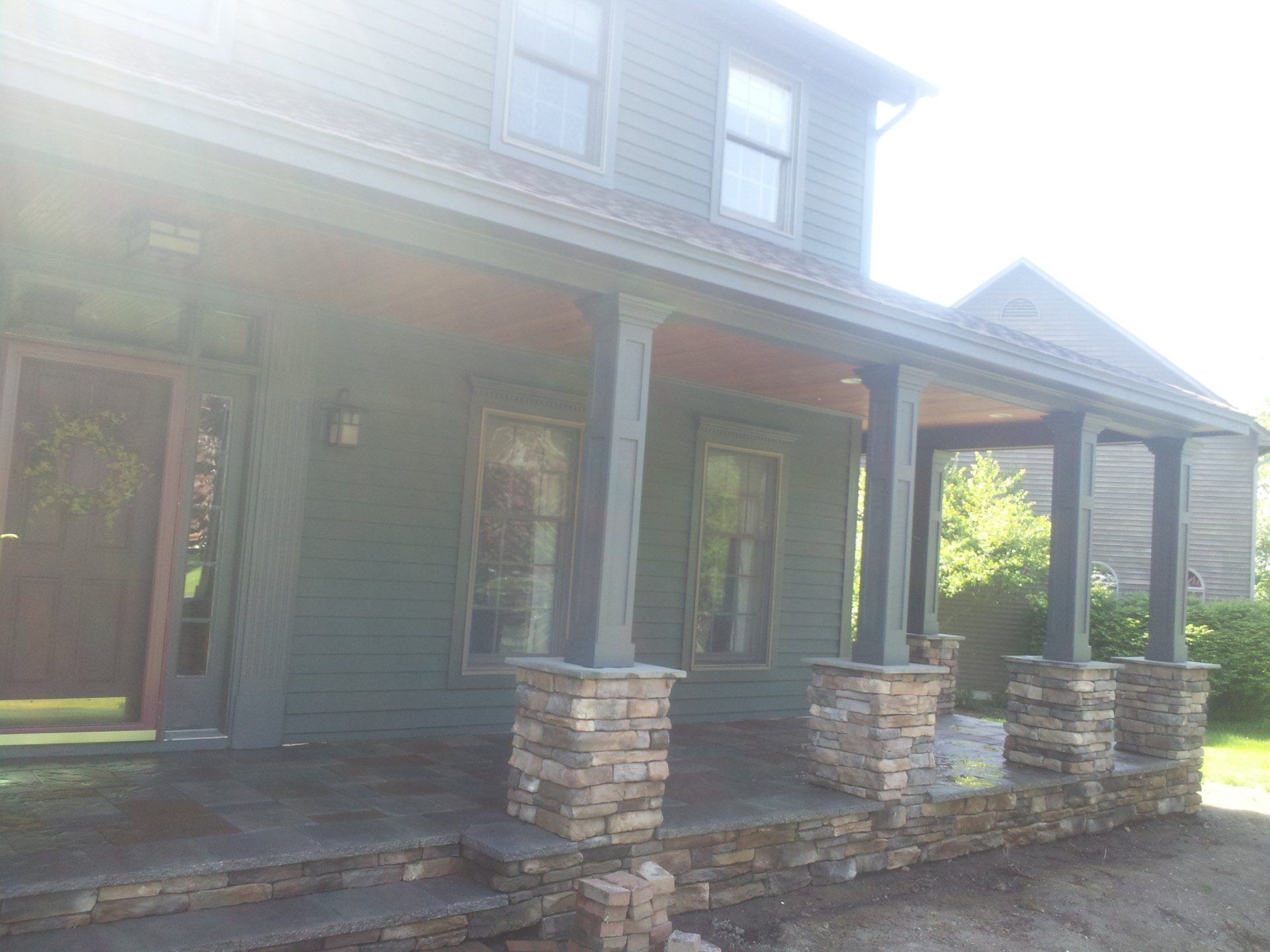 A house with a porch and stone pillars in front of it.