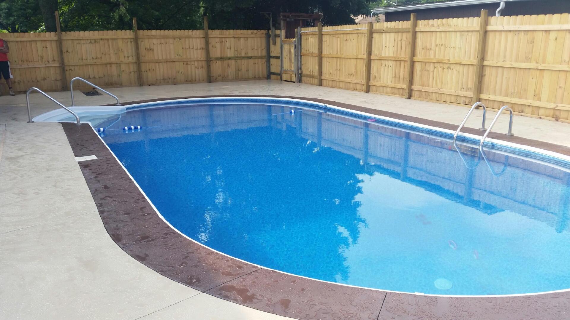 A large swimming pool with a wooden fence surrounding it