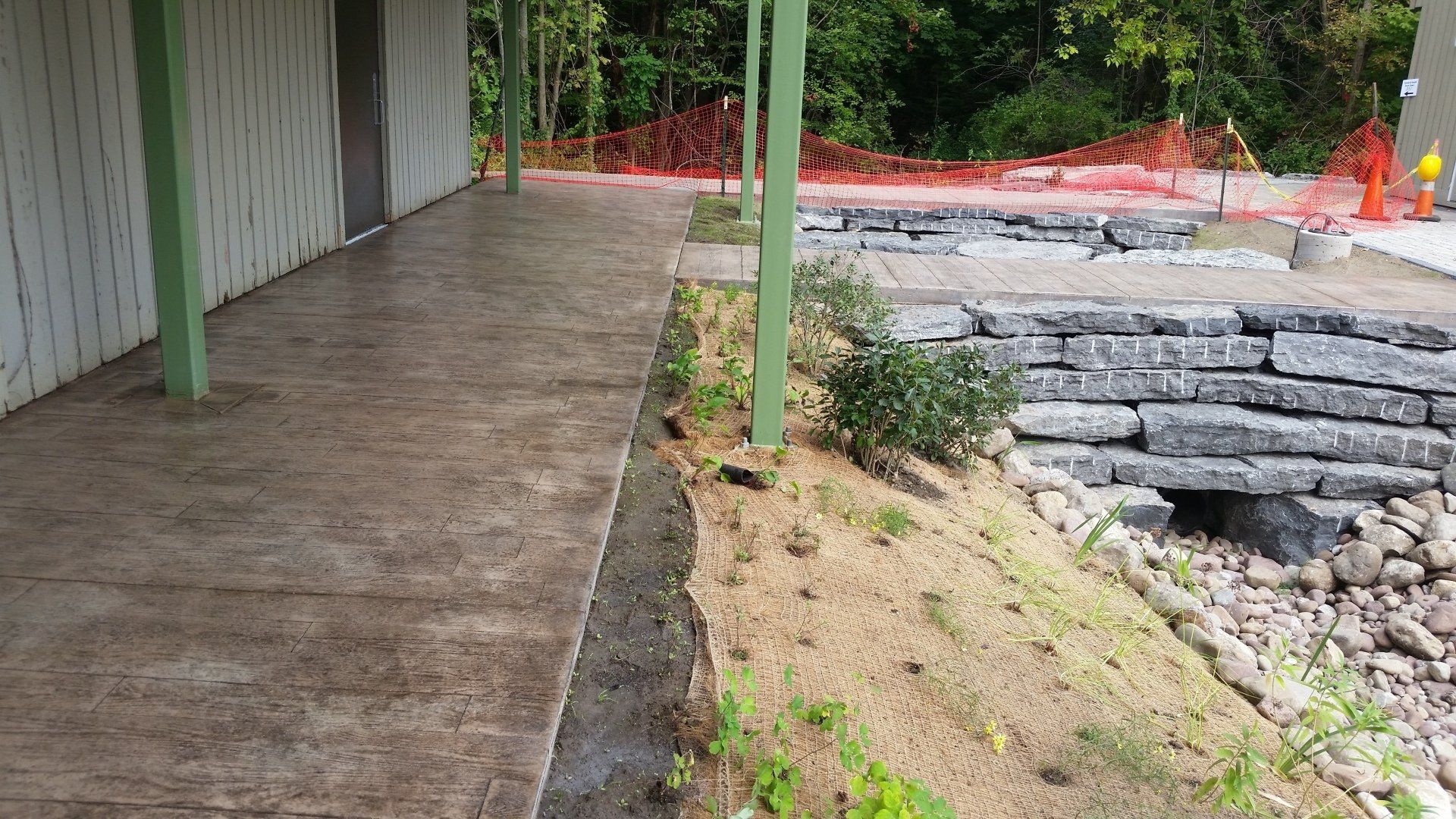 A concrete walkway is being built next to a stone wall.