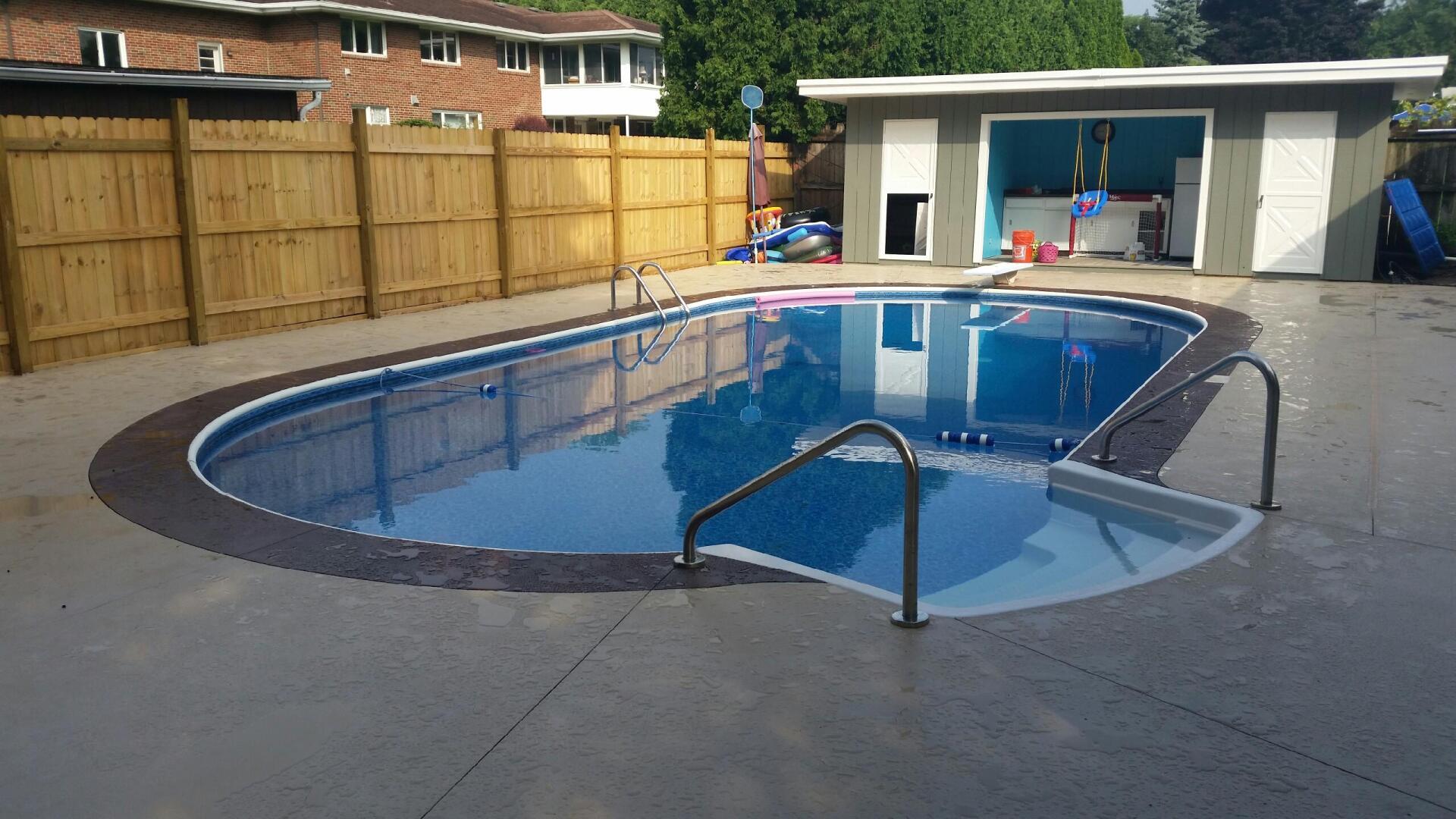 A large swimming pool with a wooden fence around it