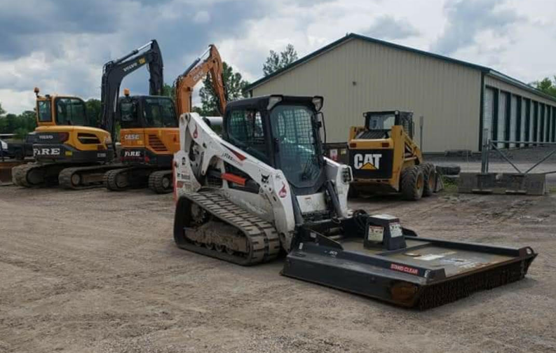 A bobcat tractor is parked in front of a building.