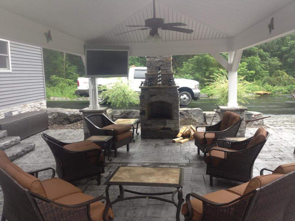 A patio with wicker furniture and a fireplace
