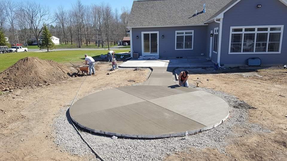 A circular concrete patio is being built in front of a house