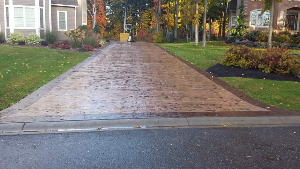 A brick driveway leading to a house with trees in the background.