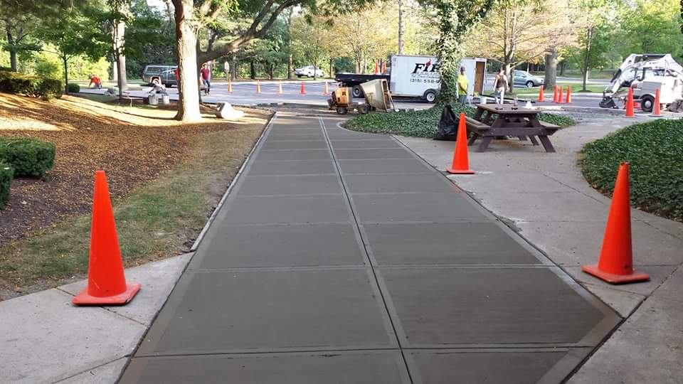 A concrete walkway with orange cones on the side of it