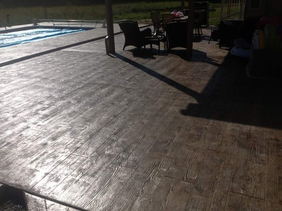 A patio with chairs and tables next to a pool.