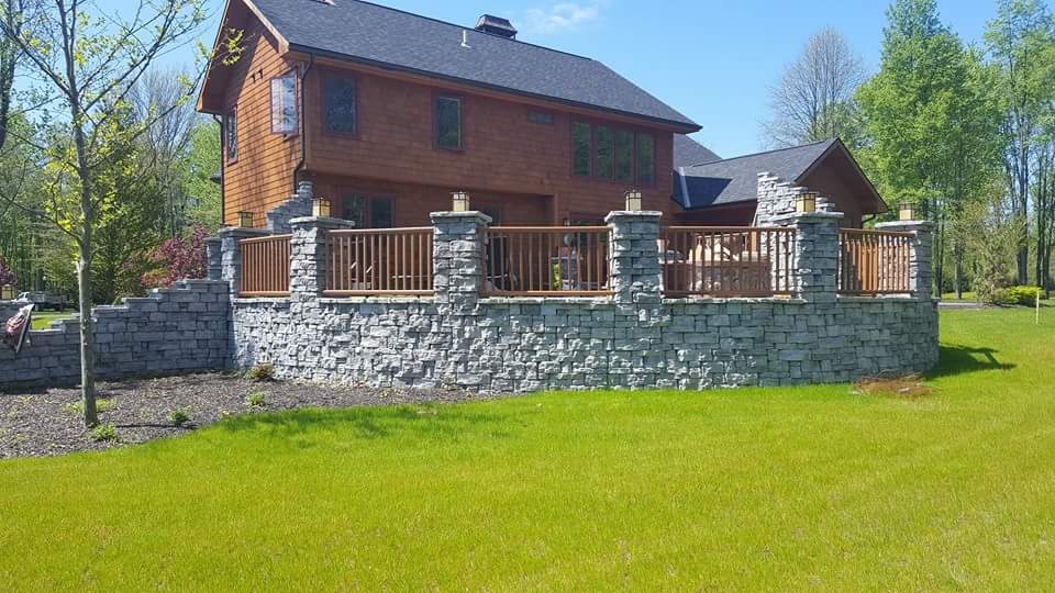 A large house with a large stone wall in front of it.