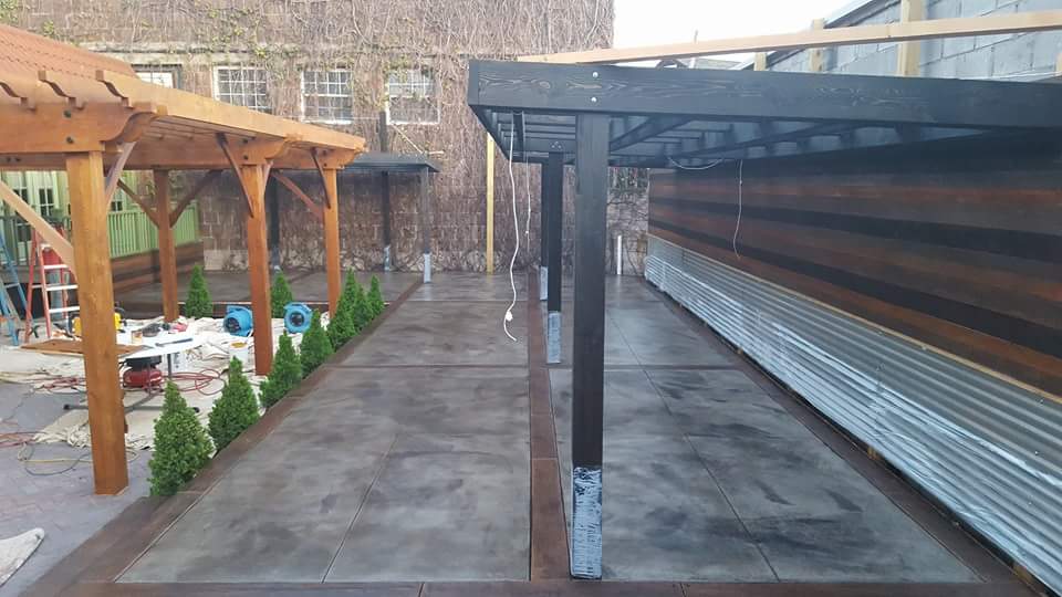 A concrete walkway with a wooden pergola in the background
