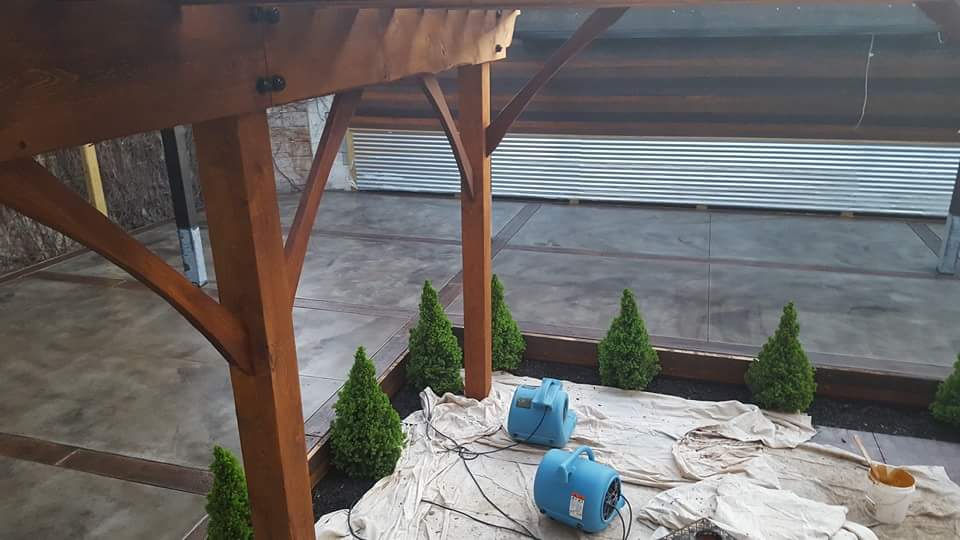 Two blue barrels are sitting under a wooden structure.