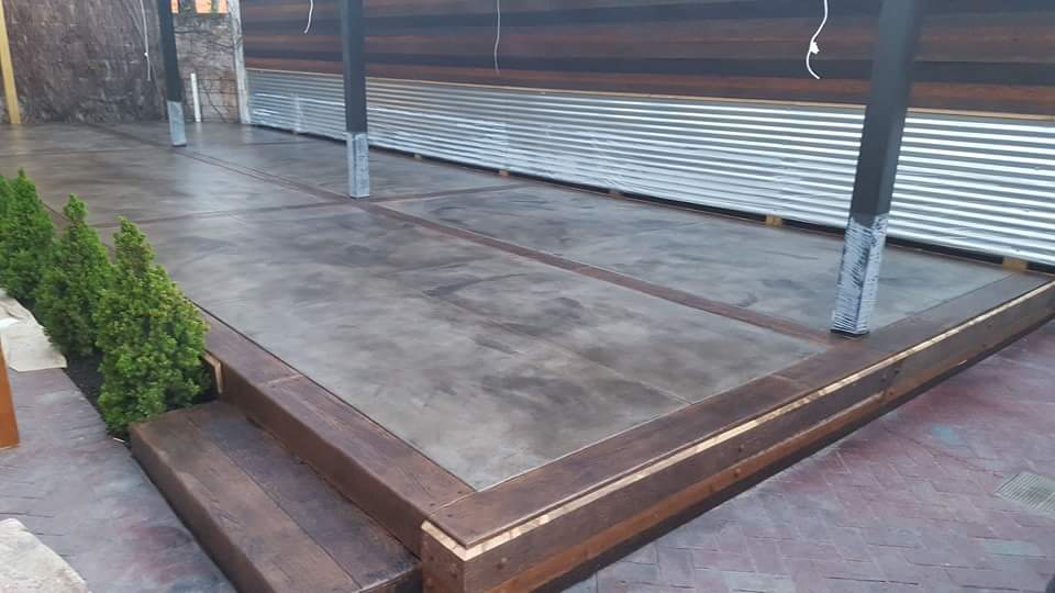 A concrete walkway with a wooden border and steps leading to a building.