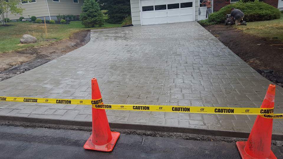 Two orange cones are sitting on the side of a driveway.