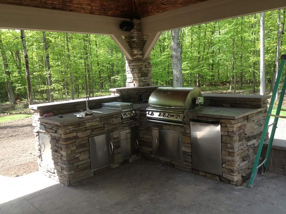 A large outdoor kitchen with a grill and a ladder.