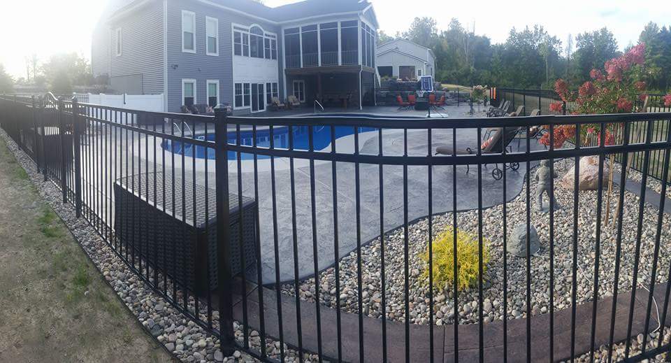 A large house with a swimming pool behind a metal fence.
