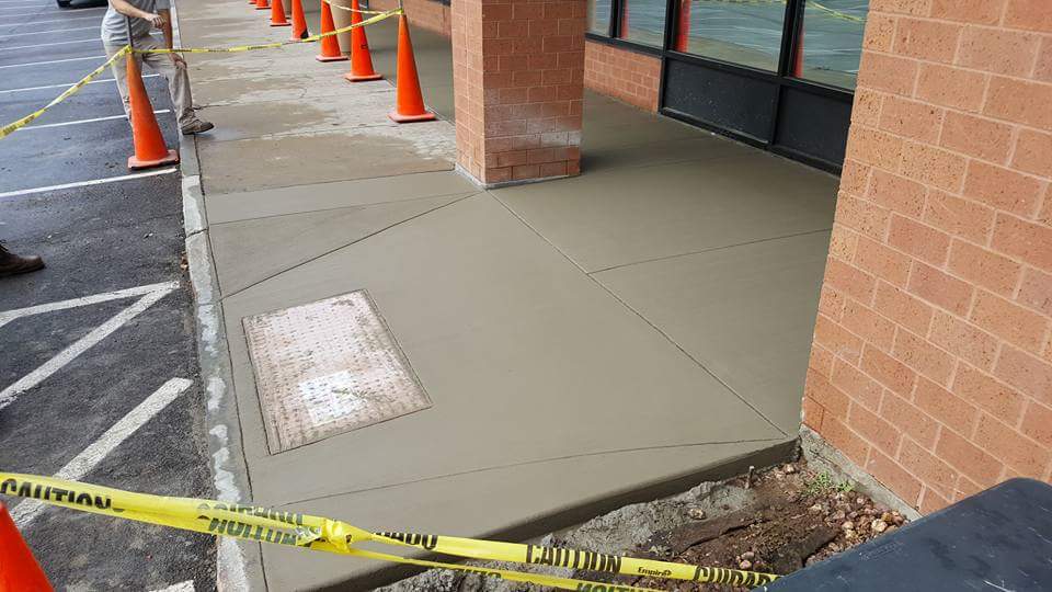 A sidewalk is being built in front of a brick building.