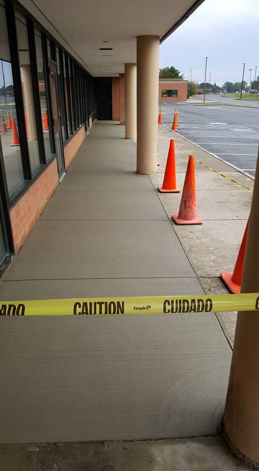 A sidewalk with orange cones and a yellow tape that says caution.