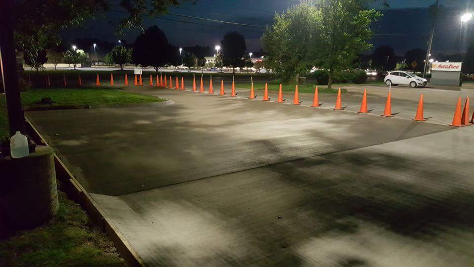 A parking lot with a lot of orange cones in it at night.