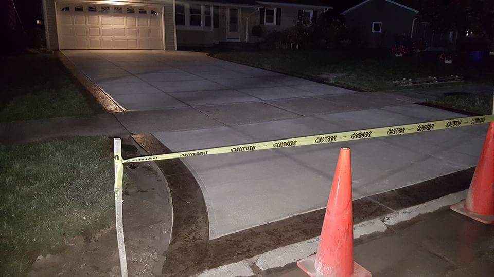 A concrete driveway is being built in front of a house at night.