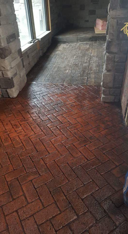 A brick floor in a room with a fireplace and a window.