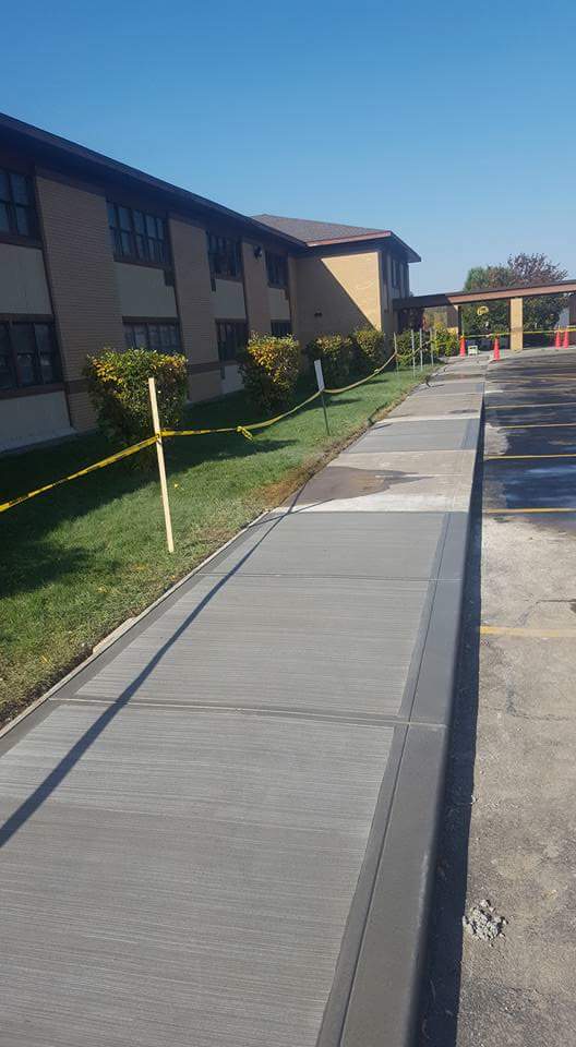 A sidewalk is being built in front of a large building.