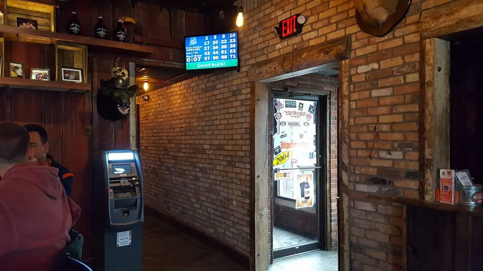 A group of people are sitting at a bar in front of a brick wall.