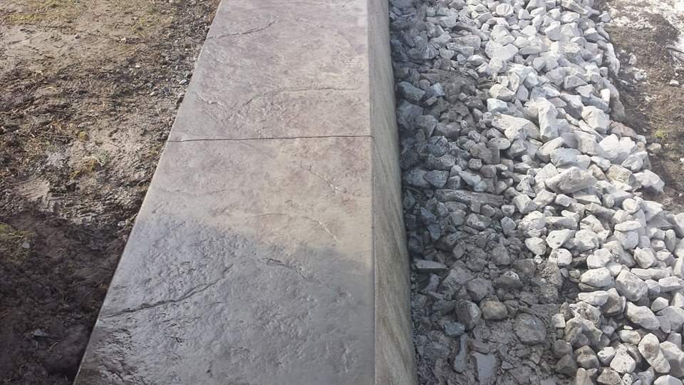 A concrete wall is being built next to a pile of rocks.