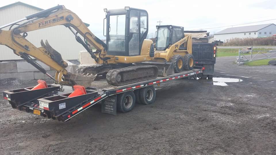 A yellow excavator is sitting on top of a trailer.