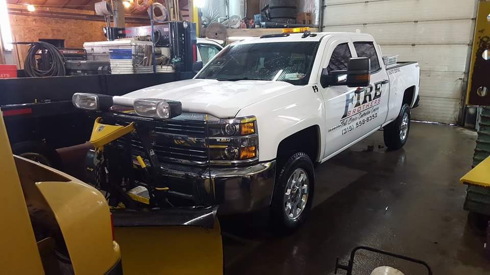 A white truck with the word fire on the side is parked in a garage.