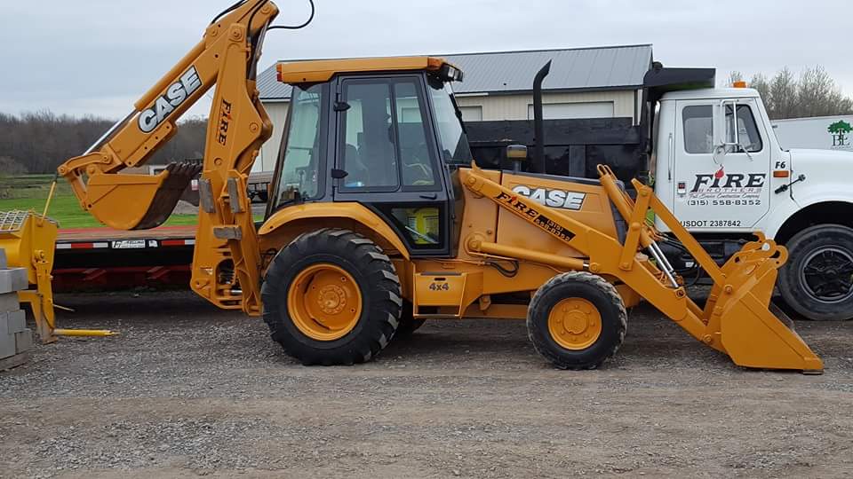 A case backhoe is parked next to a dump truck.