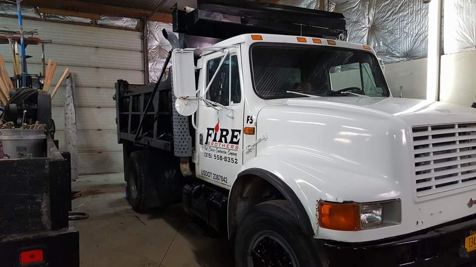 A white dump truck is parked in a garage.