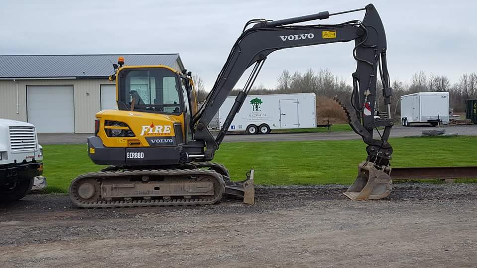 A yellow and black excavator is parked in a gravel lot.