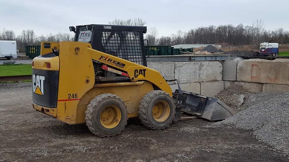 A yellow cat skid steer is parked in a dirt lot.