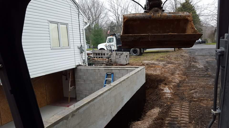 A bulldozer is digging a hole in front of a house.