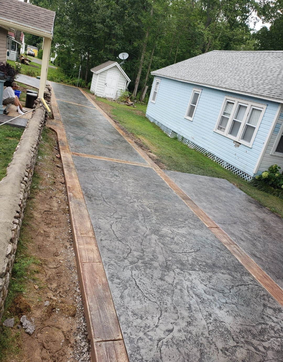 A concrete driveway is being built next to a house.
