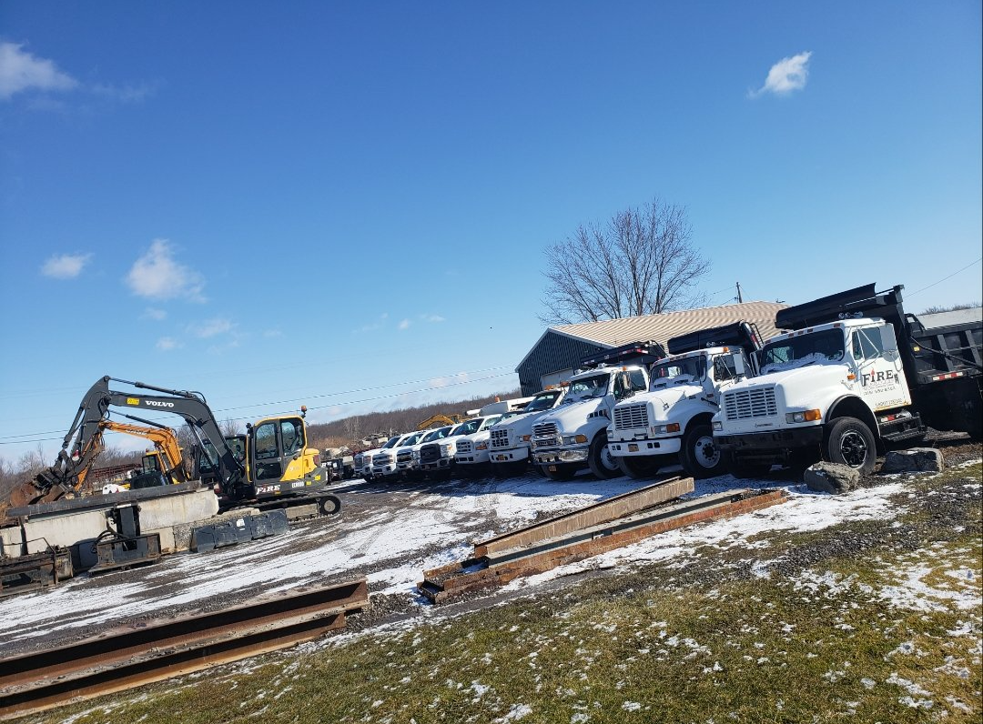 A row of trucks are parked in a snowy field.