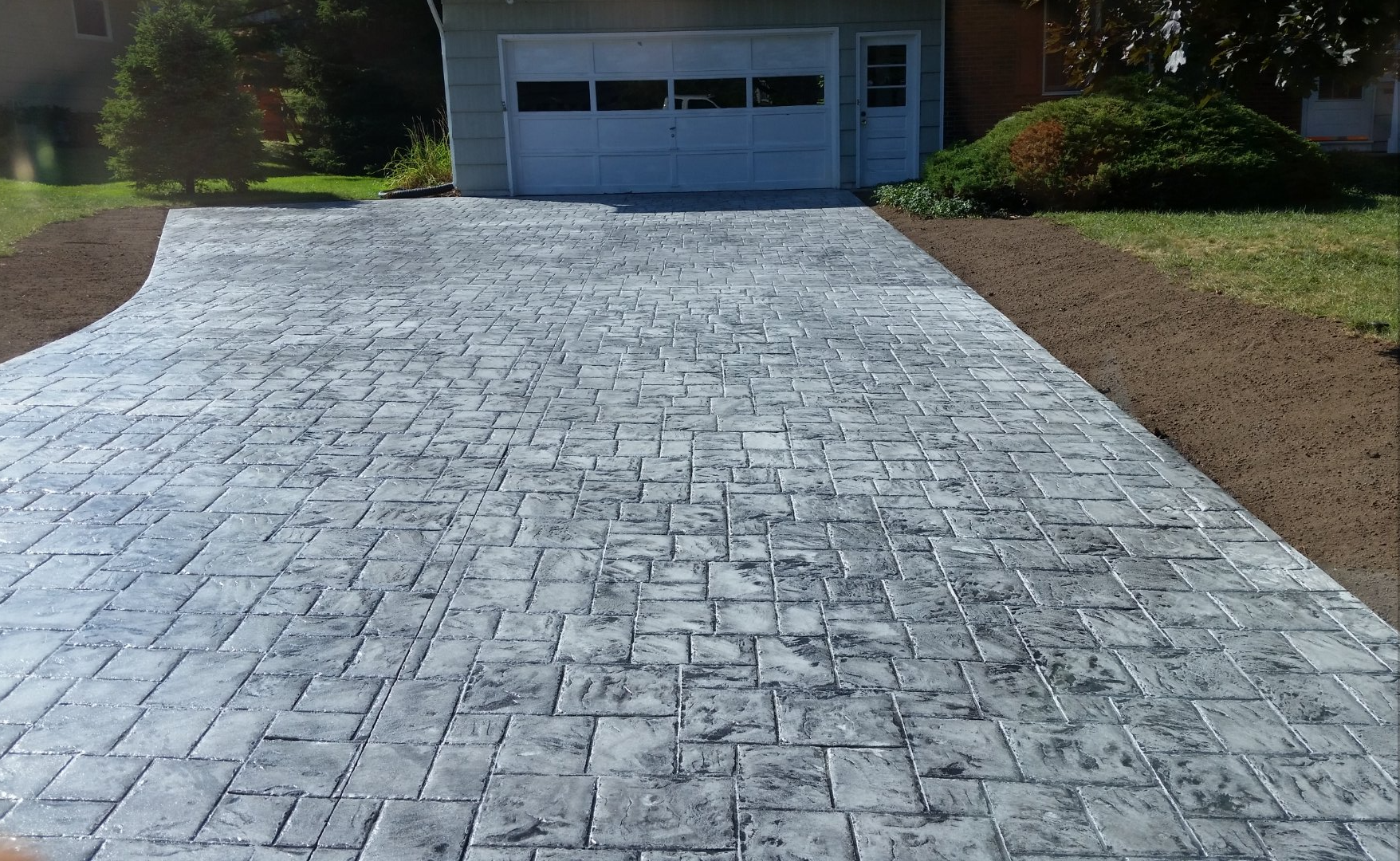 A brick driveway leading to a garage with a white garage door