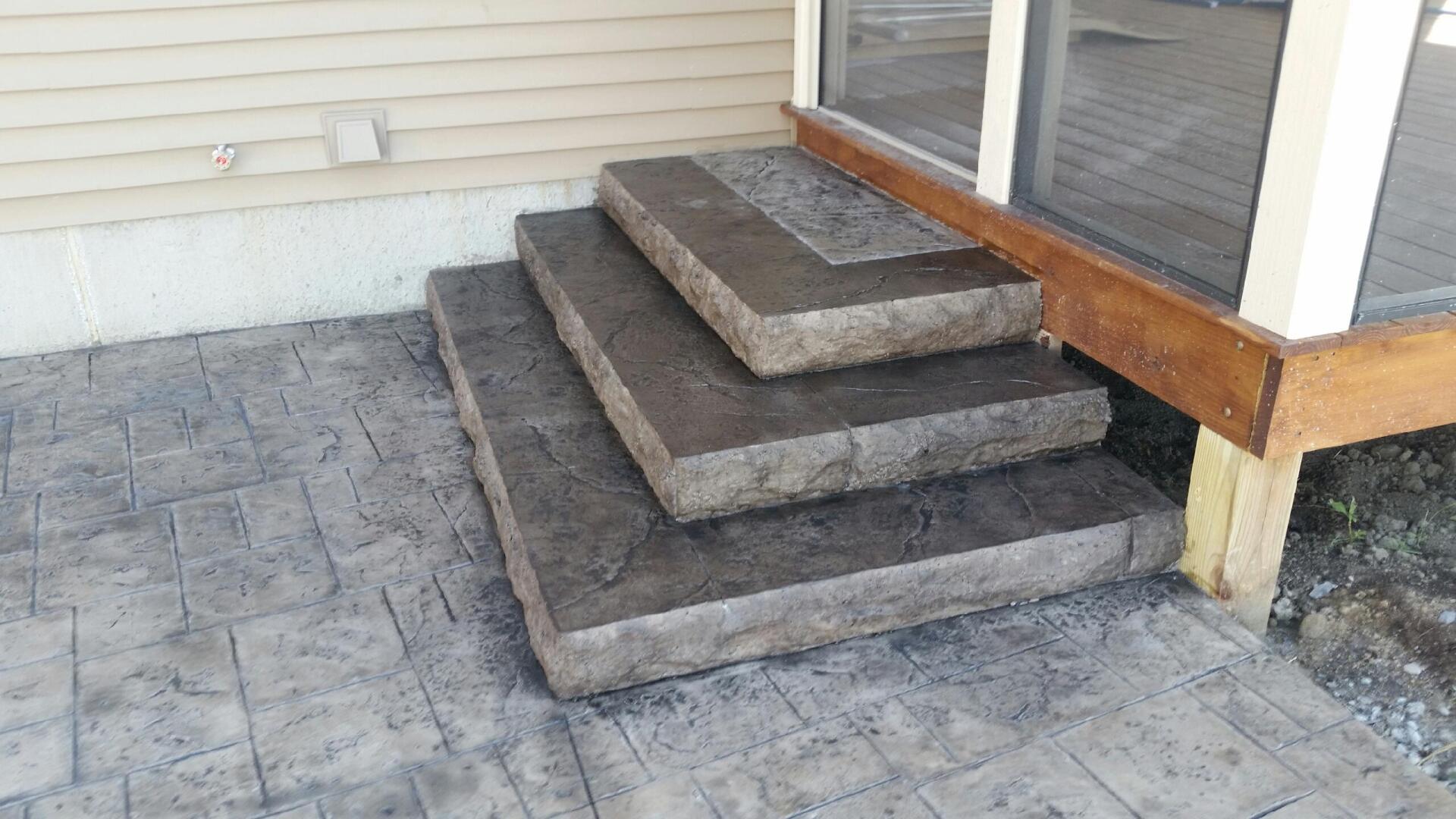 A set of concrete steps leading up to a screened in porch.