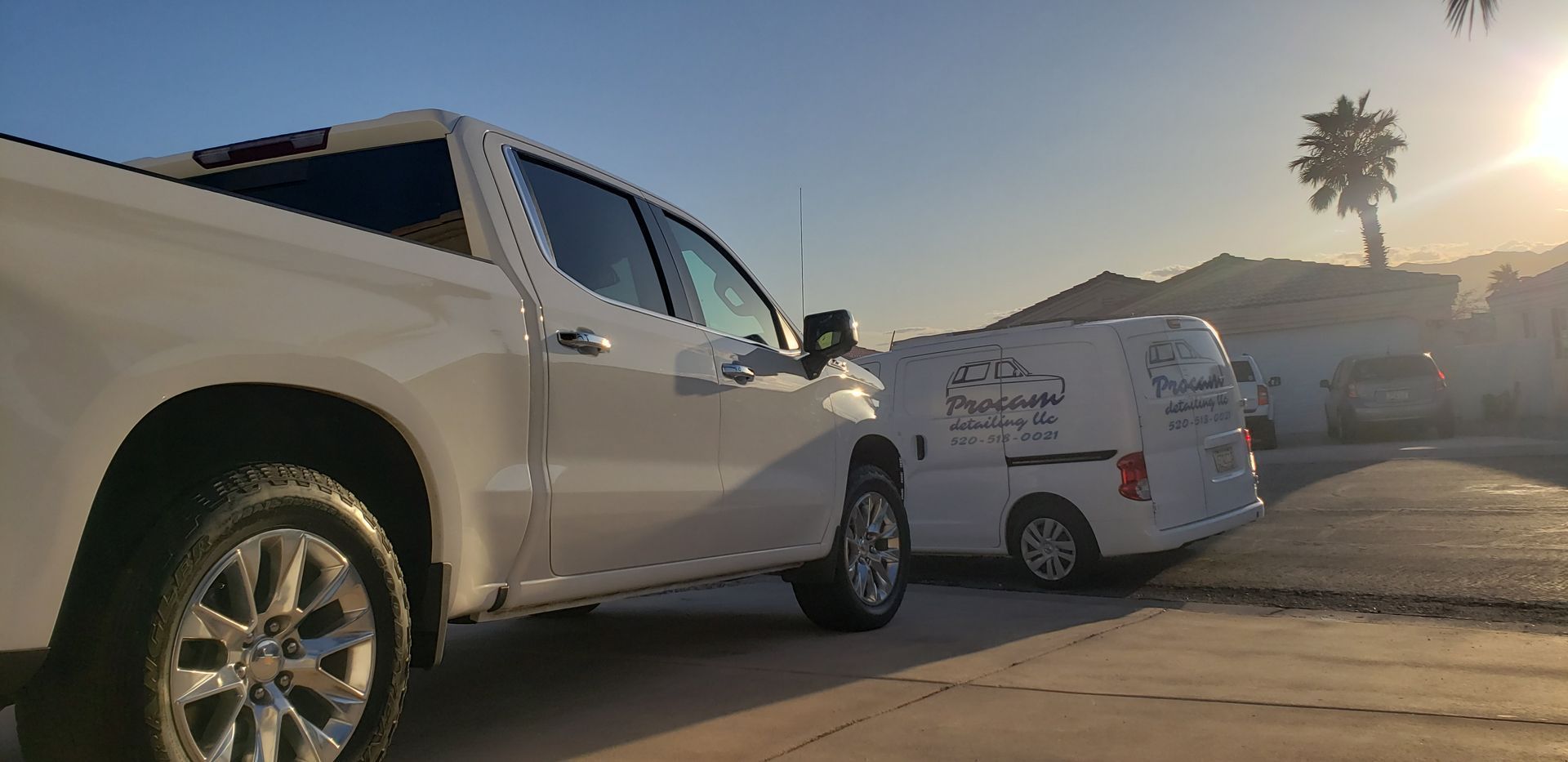 a silver truck with red wheels and tires is parked on a gravel road .