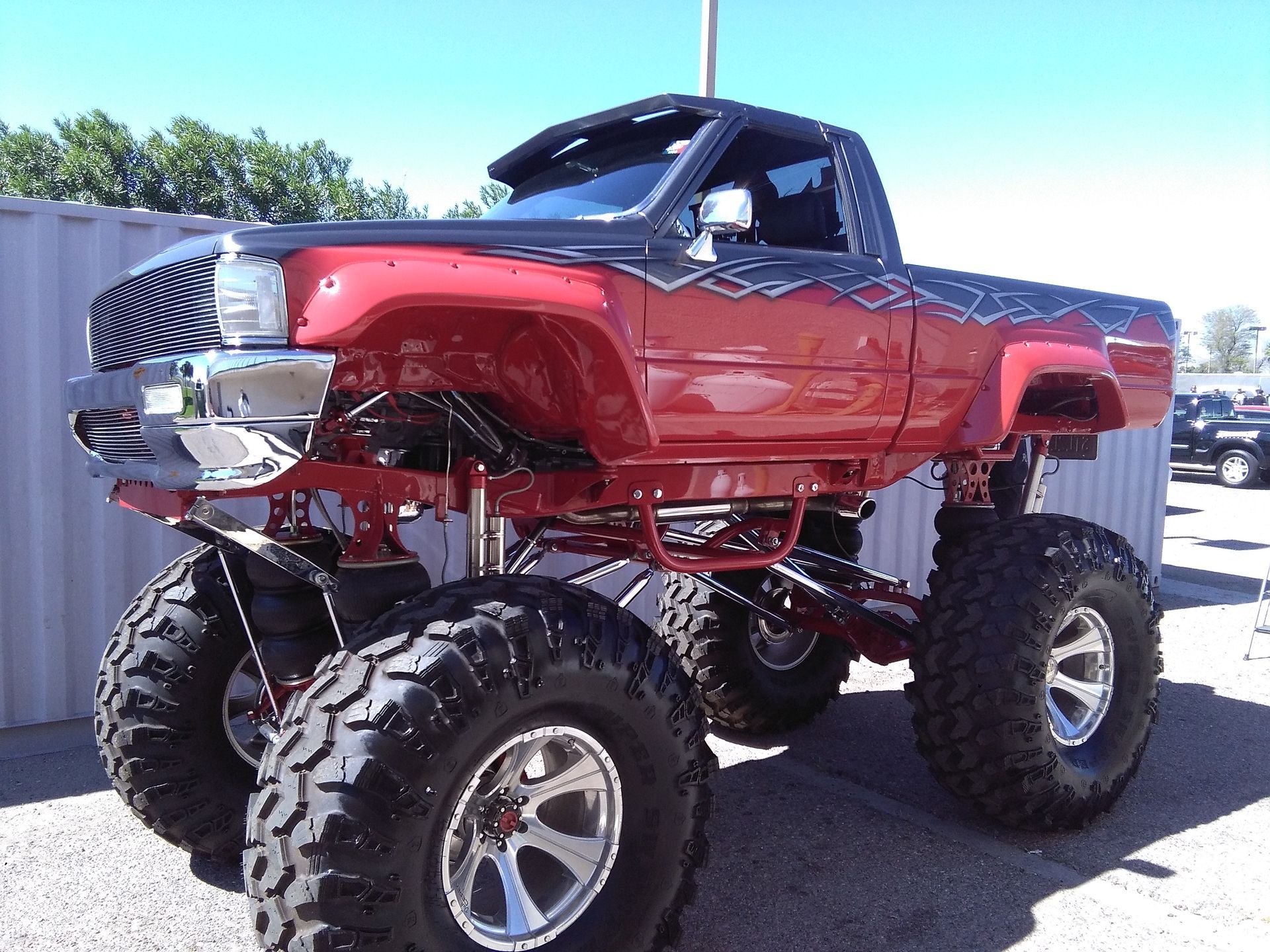 a red monster truck is parked in a parking lot