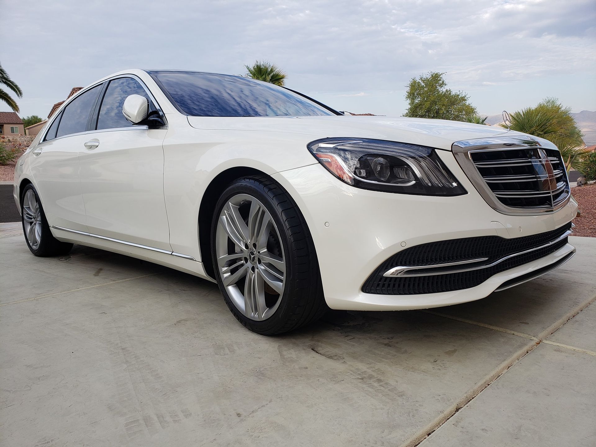 a white mercedes benz s class is parked in a driveway .