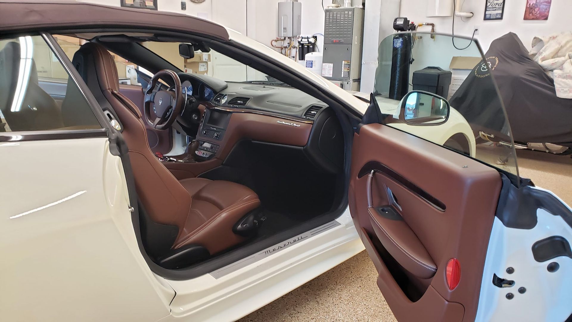 a white car with brown seats is parked in a garage with the door open .