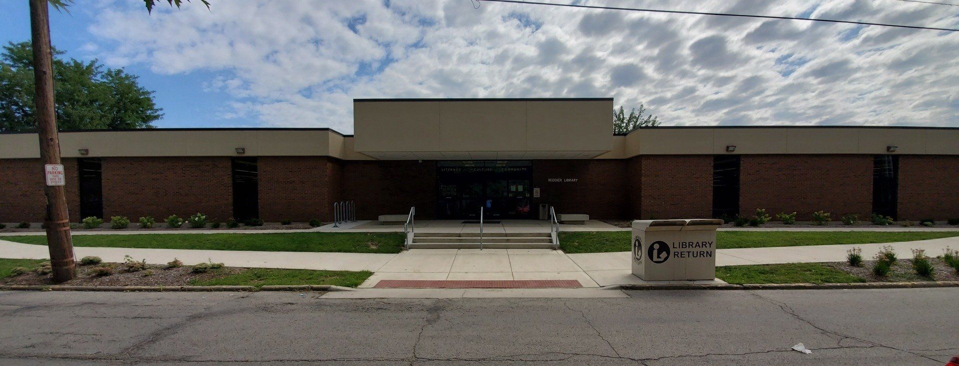 A large brick building with a white roof is sitting on the side of the road.