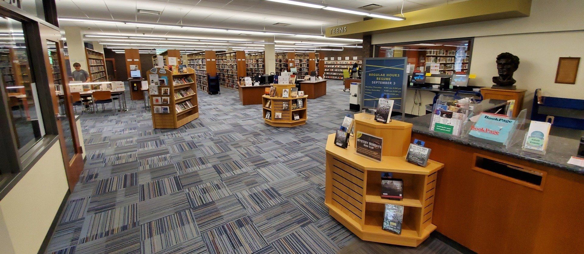 A large room with a lot of shelves and a counter in a library.