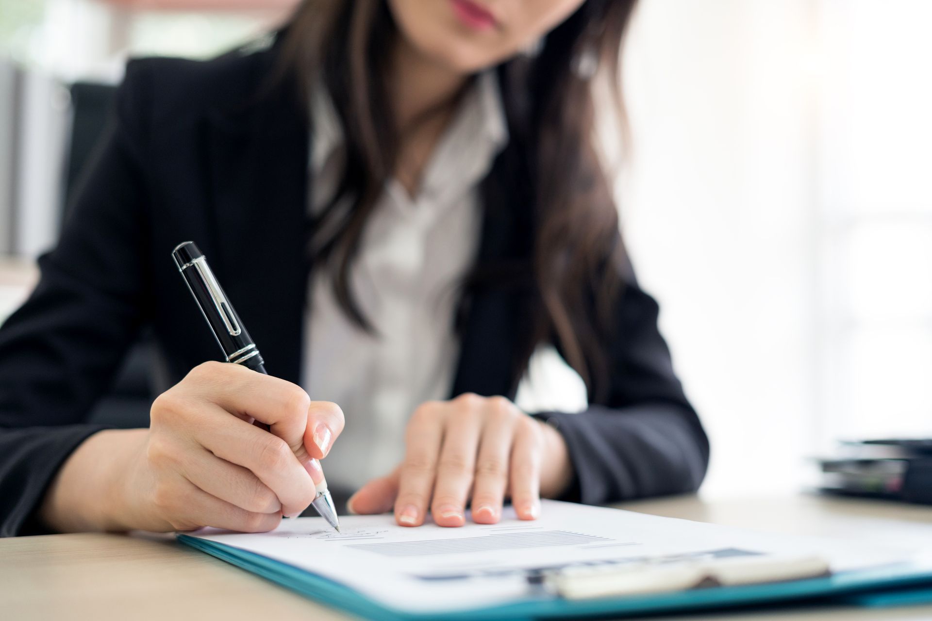 A woman is writing on a clipboard with a pen.