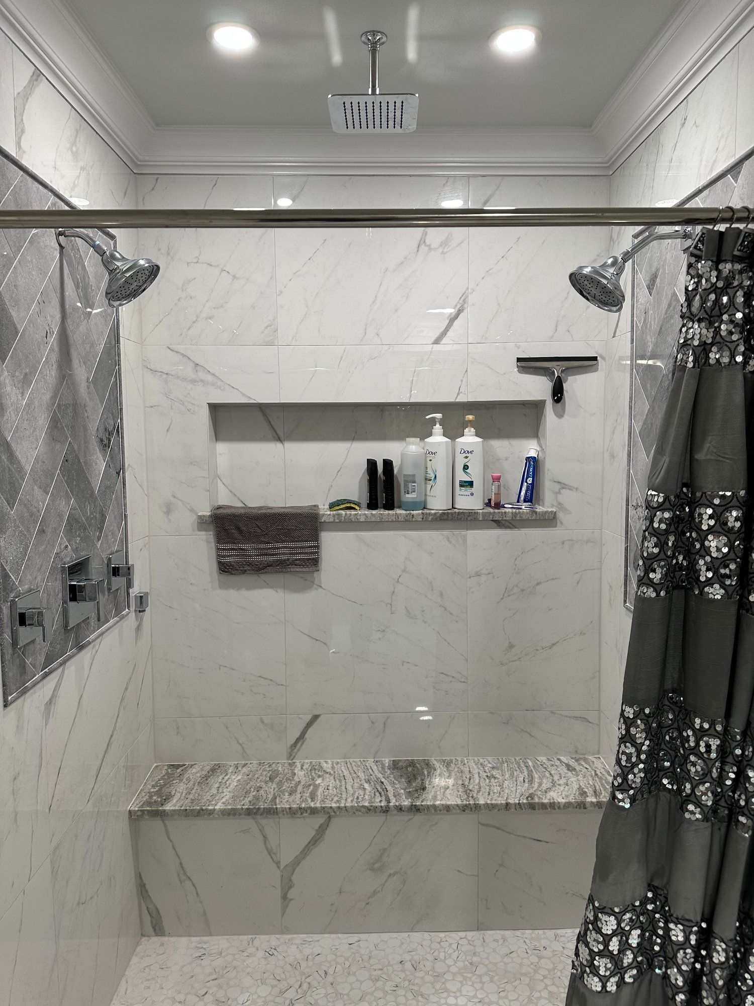 A bathroom with a walk in shower , a bench , and a shower curtain.