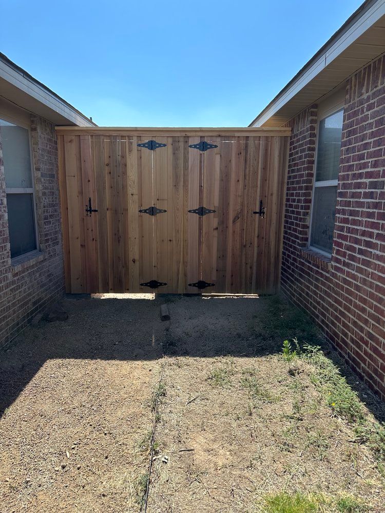 A wooden fence is between two brick houses.